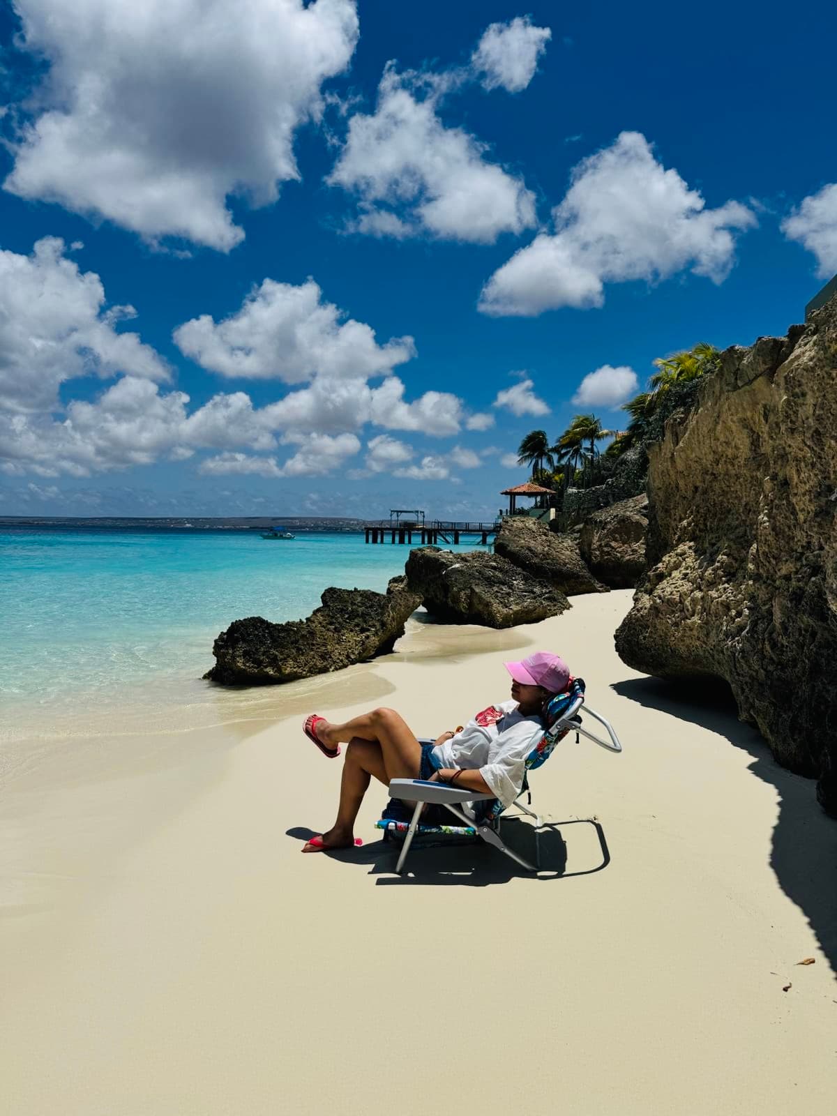 Beach chairs and umbrellas ready for delivery on a white-sand beach in Bonaire, turquoise water in the background